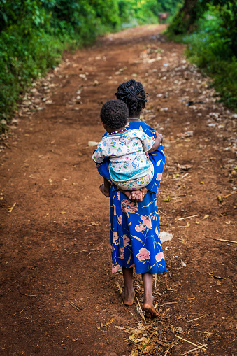 African little girl carrying her little sister in a remote village, Ethiopia, East Africa