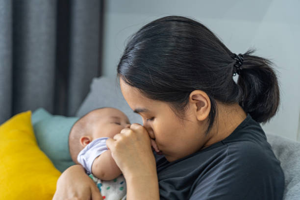 istock Asian mother kissing her baby's hand while she sleeping 1369358203
