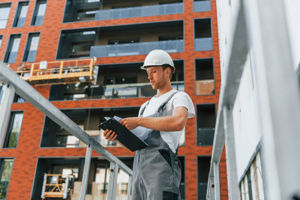 istock Manager of project. Young man working in uniform at construction at daytime 1369359032
