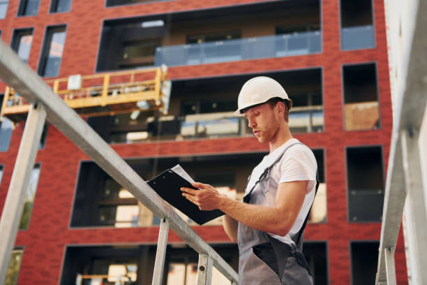 istock Manager of project. Young man working in uniform at construction at daytime 1369359046