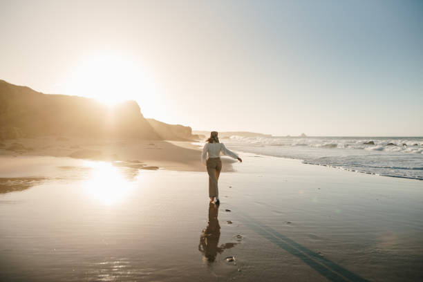 istock Young woman walking on a beach and reflection 1369359860