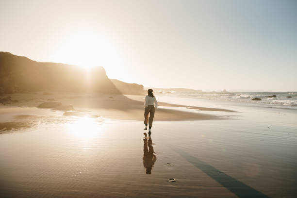 istock Young woman walking on a beach and reflection 1369360057
