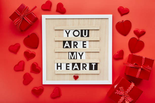 istock Letter board with hearts and gift boxes on red background. Top view. Background for Valentine's day 1369360357