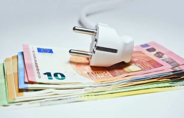 The electric plug placed on a stack of euro banknotes.