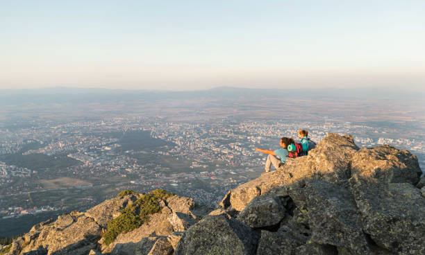 istock Tourists sitting on a rock over the valley 1369361770