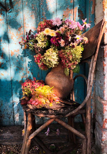 Romantic bouquet with hydrangea, aster, chrysanthemum and grapes in a retro style in the courtyard against the background of a blue old door