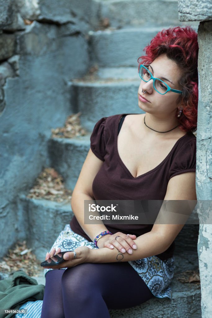 Hipster girl feeling lonely Teen with red hair sitting on stairs Overcast Stock Photo