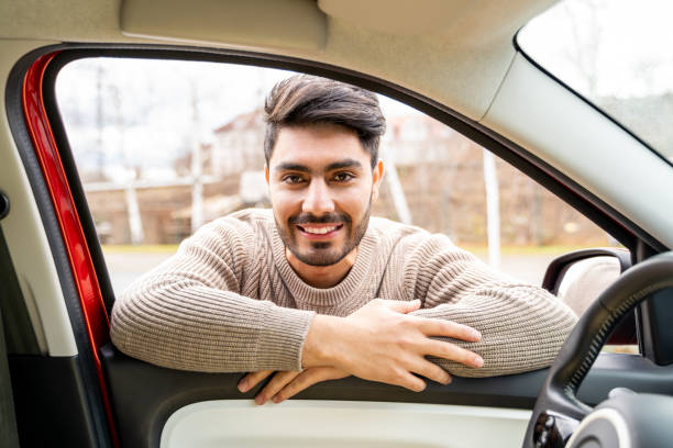istock Man casually dressed with hands holding driving wheel riding car at daytime 1369363793