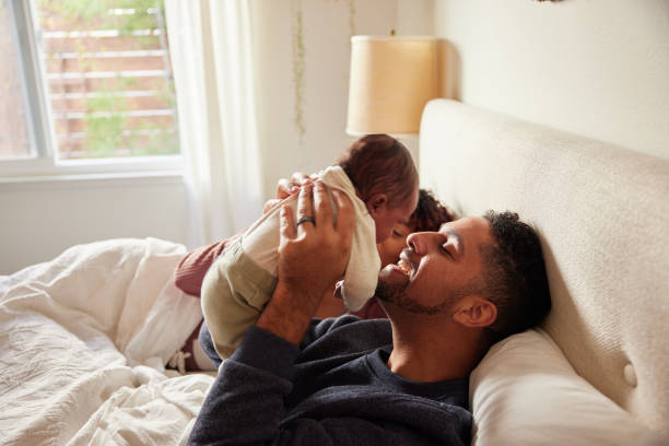 istock Dad playing with his baby boy while lying with his wife in bed 1369364261