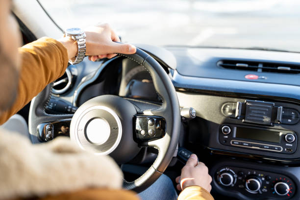 istock Man casually dressed with hands holding driving wheel starting engine with key 1369364569