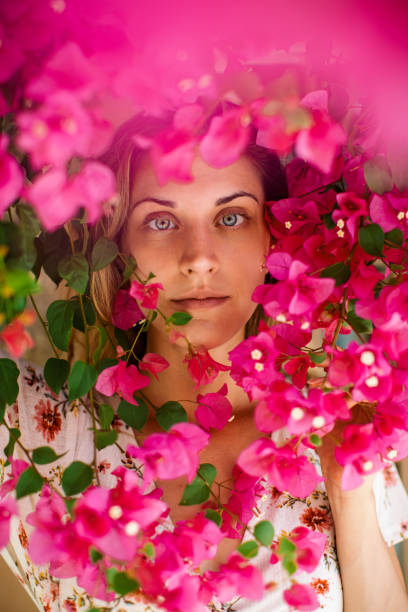 Portrait of gorgeous young woman under the blooming tree at summer. She has a blue eyes, long blond and looks very happy