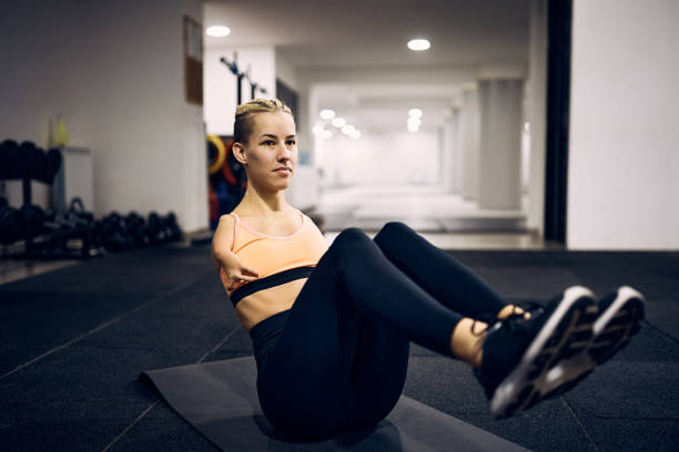 Athletic woman with a disability doing sit-ups while exercising in a gym.