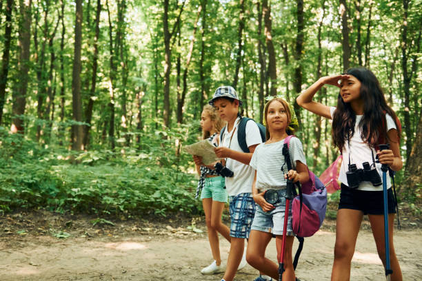 istock Front view. Kids strolling in the forest with travel equipment 1369367477