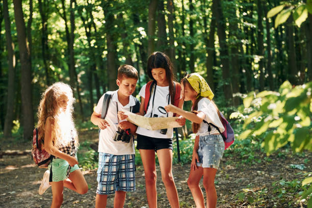 istock Using map to find a way. Kids strolling in the forest with travel equipment 1369368965