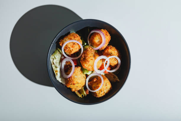 ensalada con bolas de queso fritas y cebollas rojas. luz dura, sombra profunda - vegetable basket fotografías e imágenes de stock