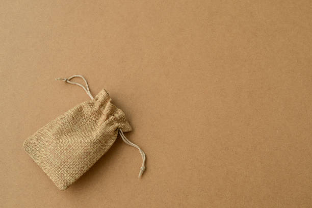 istock jute bag made on  kraft paper background, copy space. empty small sack fabric bag on brown cardboard 1369372662