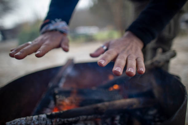 istock To warm it up, middle-aged man stretches his hands to the fire. 1369374074