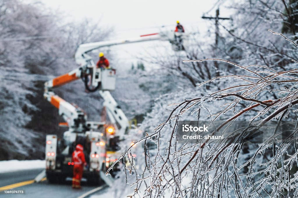 Restoring Power During Ice Storm Linesman work to restore power during an intense ice storm. Power Line Stock Photo