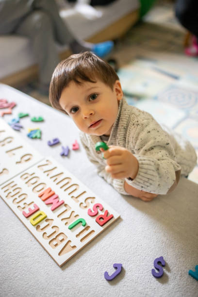 istock Cute boy holding wooden letter puzzle piece 1369374938