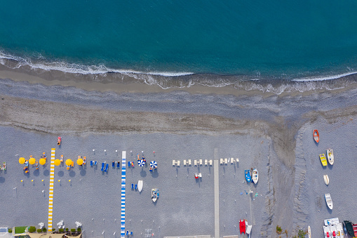 Tourists relaxing on Mediterranean pebble sea beach, aerial top view