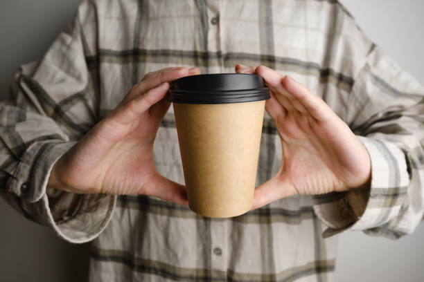 istock Disposable paper cup close-up. Eco material. Glass for hot drinks. Empty space for text, mockup. Craft paper cup with coffee in a female hand. Coffee to go concept 1369376512