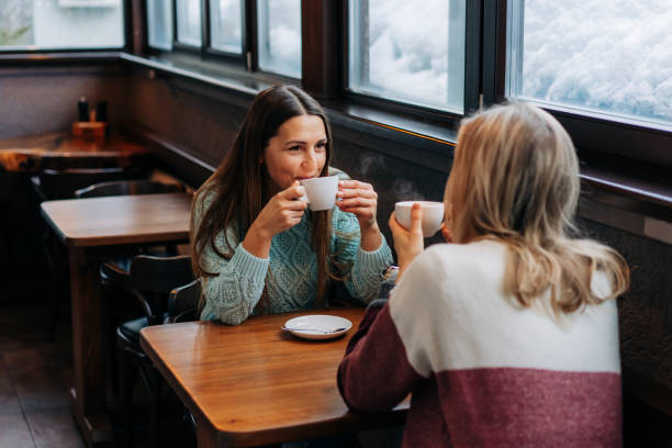 istock Two happy women having leisure drink tea and chat in a cafe. 1369377311