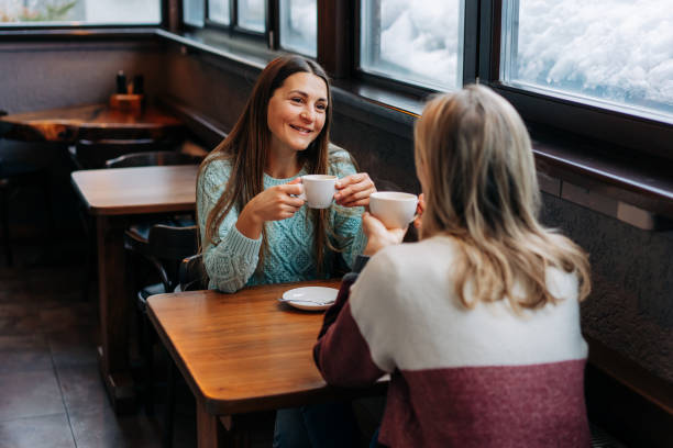uśmiechnięta brunetka rozmawiająca z przyjaciółką w kawiarni. - apres ski friendship skiing enjoyment zdjęcia i obrazy z banku zdjęć