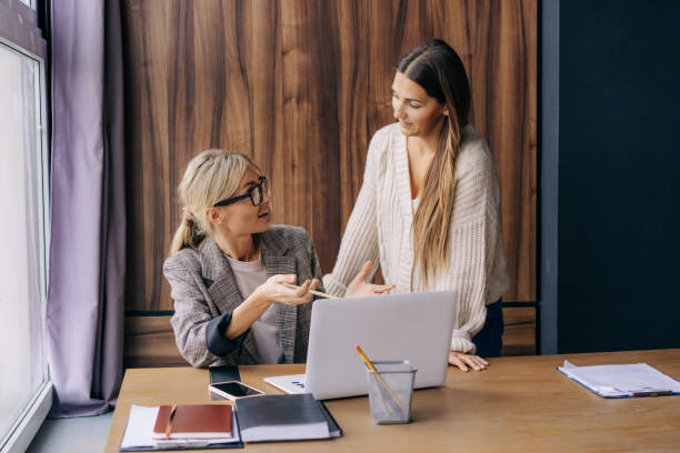 istock Two female colleagues at a working office place are discussing a project. 1369377328