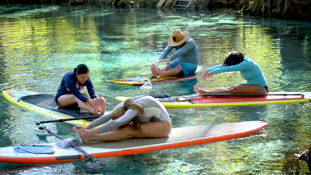 Four people practicing yoga on paddleboards