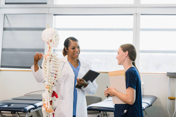 maestra hace gestos al esqueleto humano mientras ayuda al estudiante - anatomy classroom human skeleton student fotografías e imágenes de stock