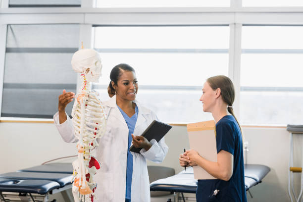 une enseignante fait des gestes au squelette humain tout en aidant l’élève - anatomy classroom human skeleton student photos et images de collection