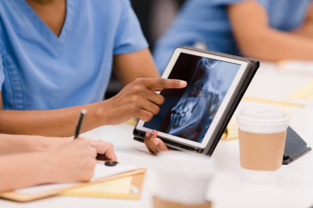 Unrecognizable nursing student points to x-ray of skull on tablet