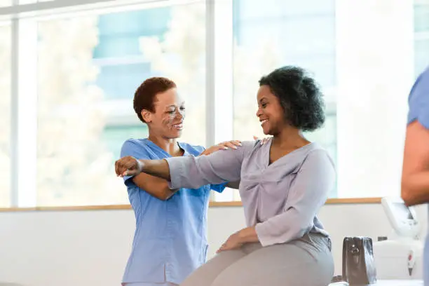 Photo of Therapist and female patient smile during shoulder massage