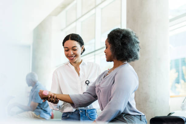 istock Therapist smiles while guiding businesswoman's hand weight exercises 1369379591