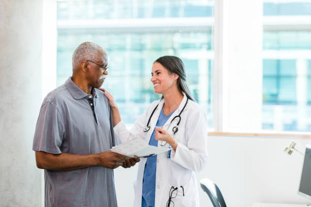 doktor lächelt und versucht, traurigen älteren mann zu ermutigen - patient retirement senior adult hospital stock-fotos und bilder