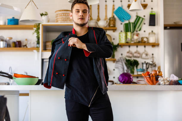 istock Young male chef getting dressed, preparing to cook 1369383787