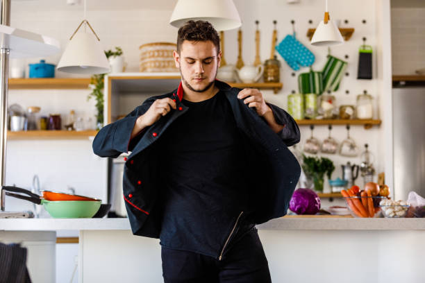 Young male chef putting on his uniform before preparing food