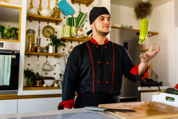 istock Young male chef playfully throwing a zucchini he is about to cut 1369384596