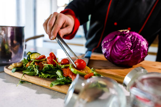 Chef adding roasted cherry tomatoes on top of a dish he prepared