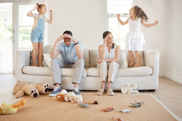istock Shot of a young couple looking frustrated while their two daughters play around them 1369385686