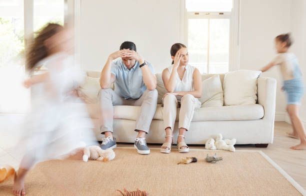 istock Shot of a young couple looking frustrated while their two daughters play around them 1369385694