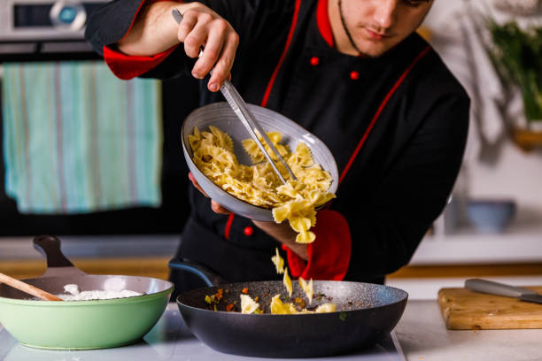 istock Front view of professional chef adding bowtie pasta into a sauce 1369385878