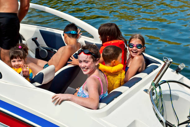 Children rest on a motor boat. Boys and girls are sitting in a speedboat. Active recreation on the water in summer. Children rest on a motor boat. Boys and girls are sitting in a speedboat. Active recreation on the water in summer. family motorboat stock pictures, royalty-free photos & images