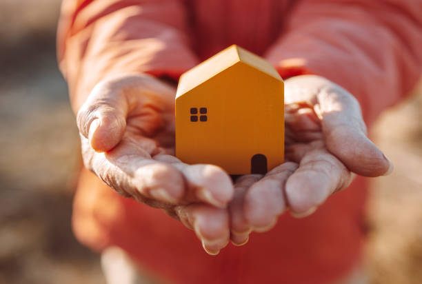 mão feminina segura uma casa de madeira em miniatura. investimento imobiliário e conceito de imobiliário imobiliário - house human hand choice real estate - fotografias e filmes do acervo