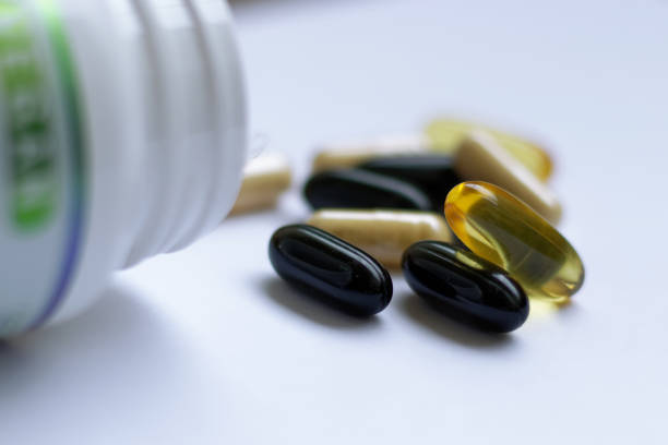 разноцветные таблетки стеки, выплескивающиеся из бутылки - vitamin a vitamin b complex pill bottle medicine стоковые фото и изображения