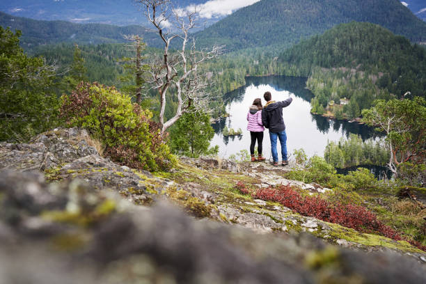 istock Couple standing on a ridge overlooking a lake and forest 1369390975