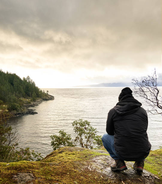istock Man looking out at the ocean during a hike on an overcast day 1369391031