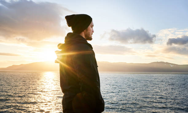 istock Man deep in thought while looking out at the ocean during a hike 1369391147