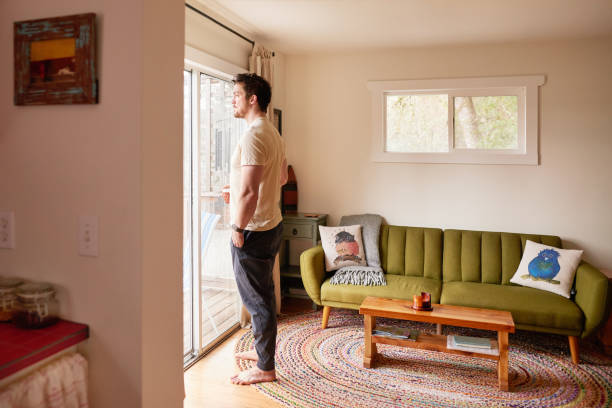 istock Man drinking coffee while looking at the view from patio windows 1369391179