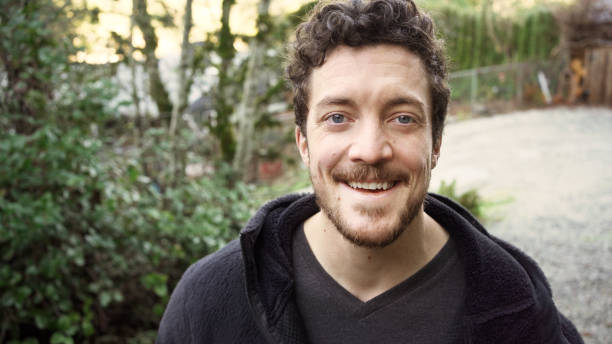 istock Young man smiling while standing outside in his yard 1369391301